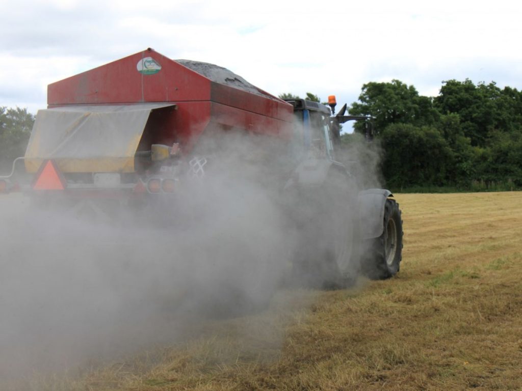 Tractor spreading Hi-Calcium Agri Lime to a green field.